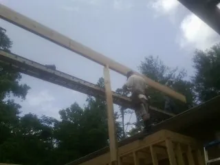 Carpenter setting a ridge beam over a new addition frame — Ice Dam Removal by Roofing Brothers in Kellerton