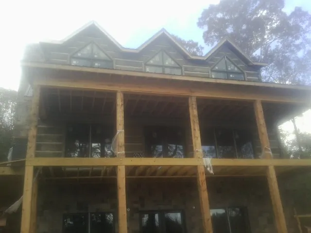Dormers and porch framing on a large log home under construction — Roof Coating work by our crew in Kellerton