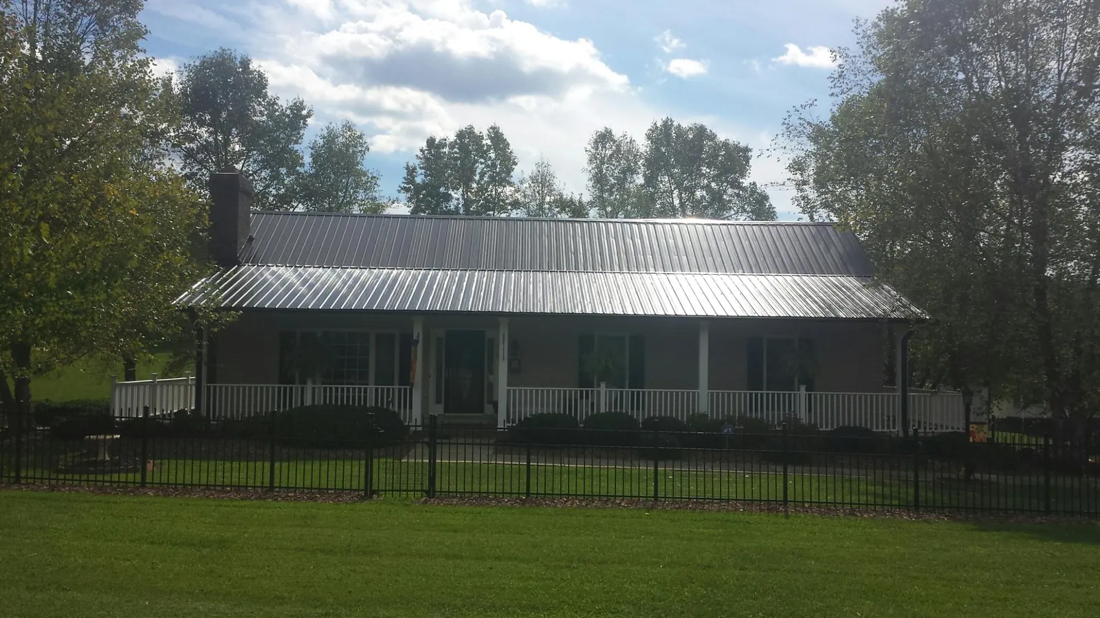 Gray metal roof on a brick ranch with a full width front porch — Gutter Guard Installation work by our crew in Kellerton
