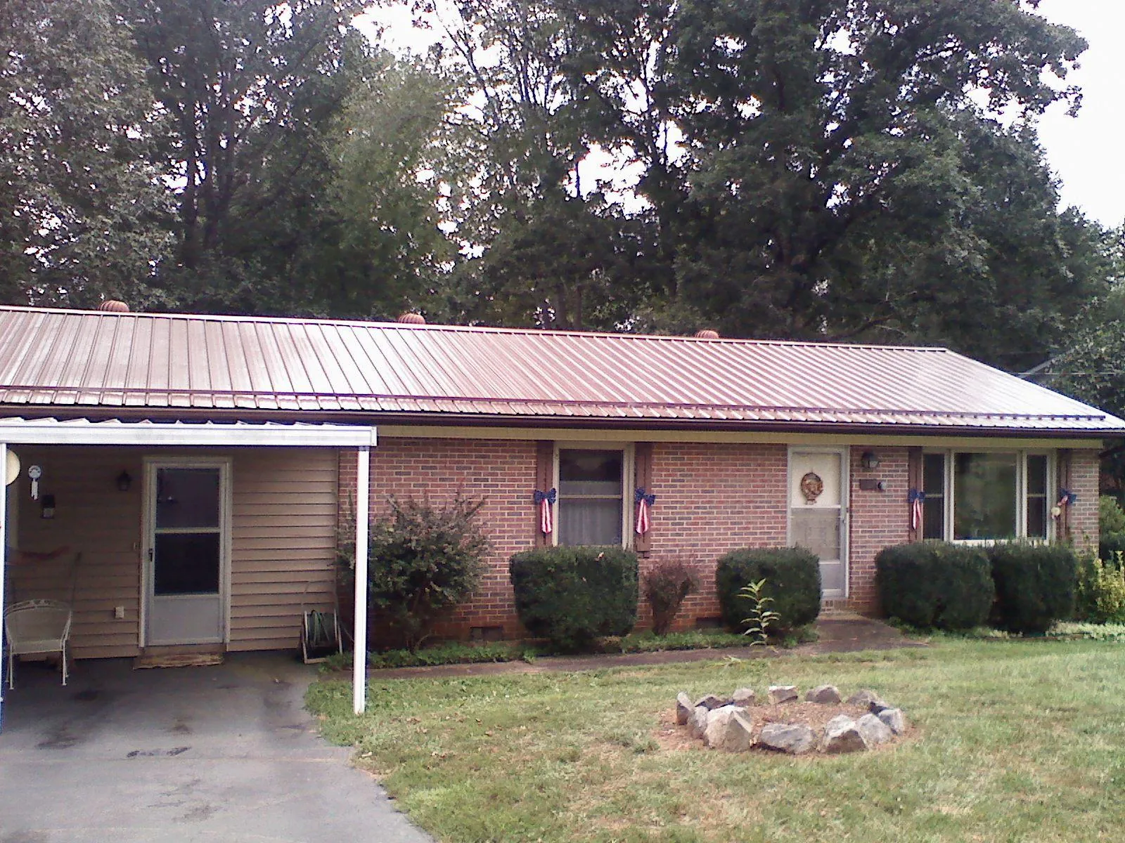 Bronze metal roof and carport on a brick ranch home — Roof Repair work by our crew in Kellerton