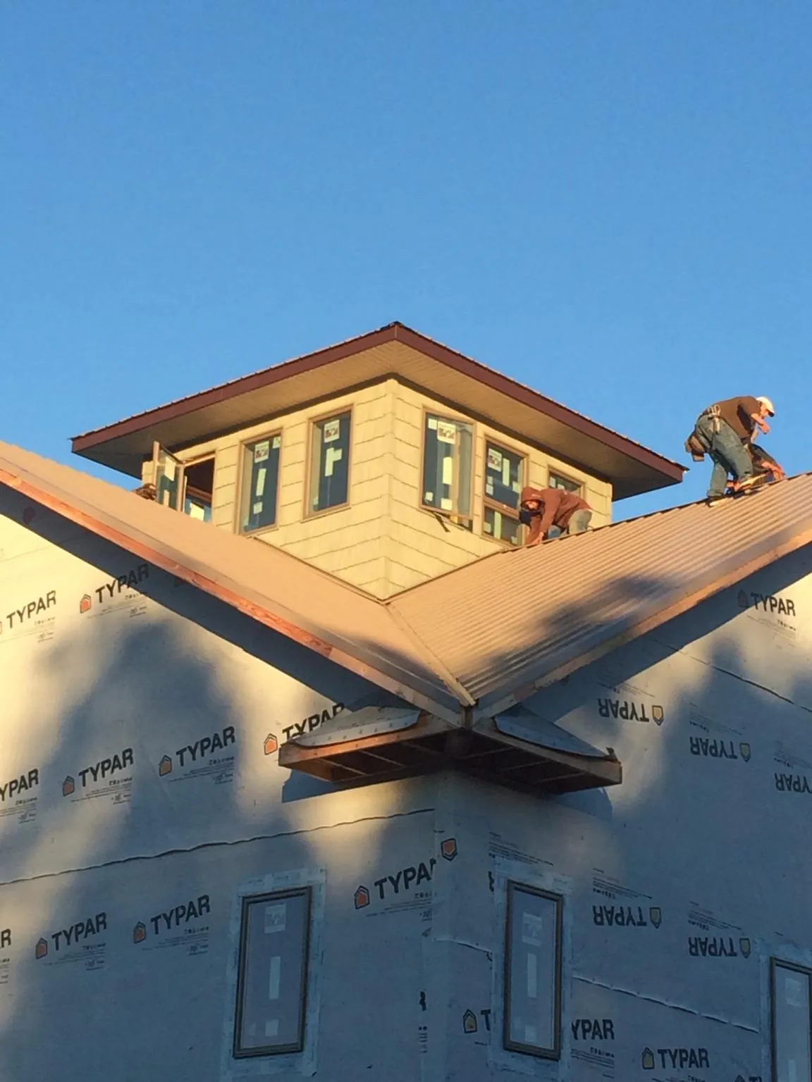 Roofers working around a rooftop cupola on a new metal roof at sunset — Roof Waterproofing in Kellerton by Roofing Brothers